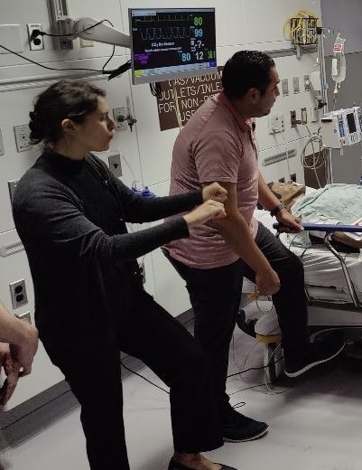 A woman standing beside another person in a hospital room